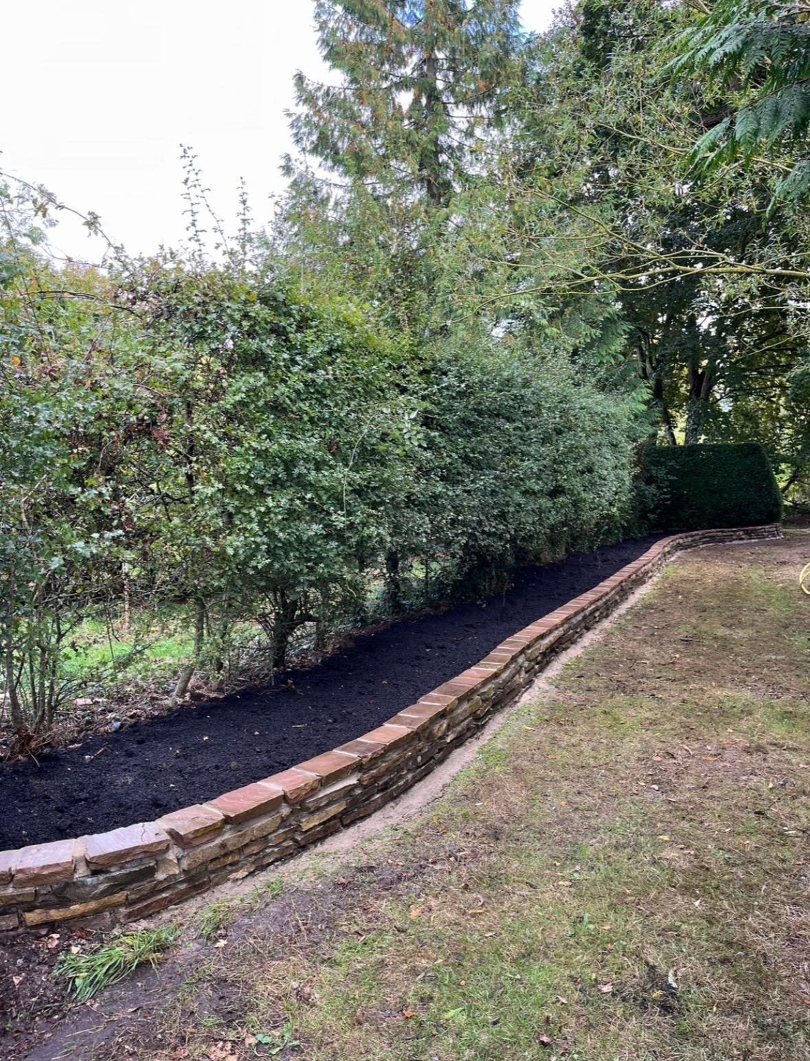 Curved stone wall with mulched border